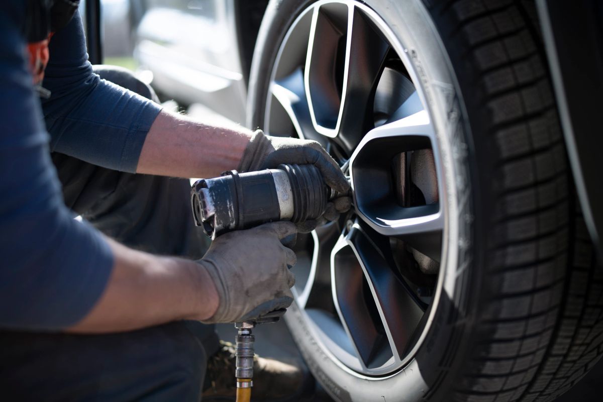 A mechanic's close-up view using an impact wrench on a wheel.