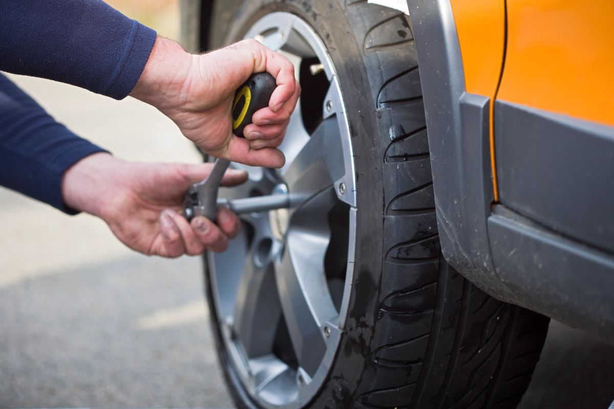 A person's hands removing a wheel lock with a socket tool.