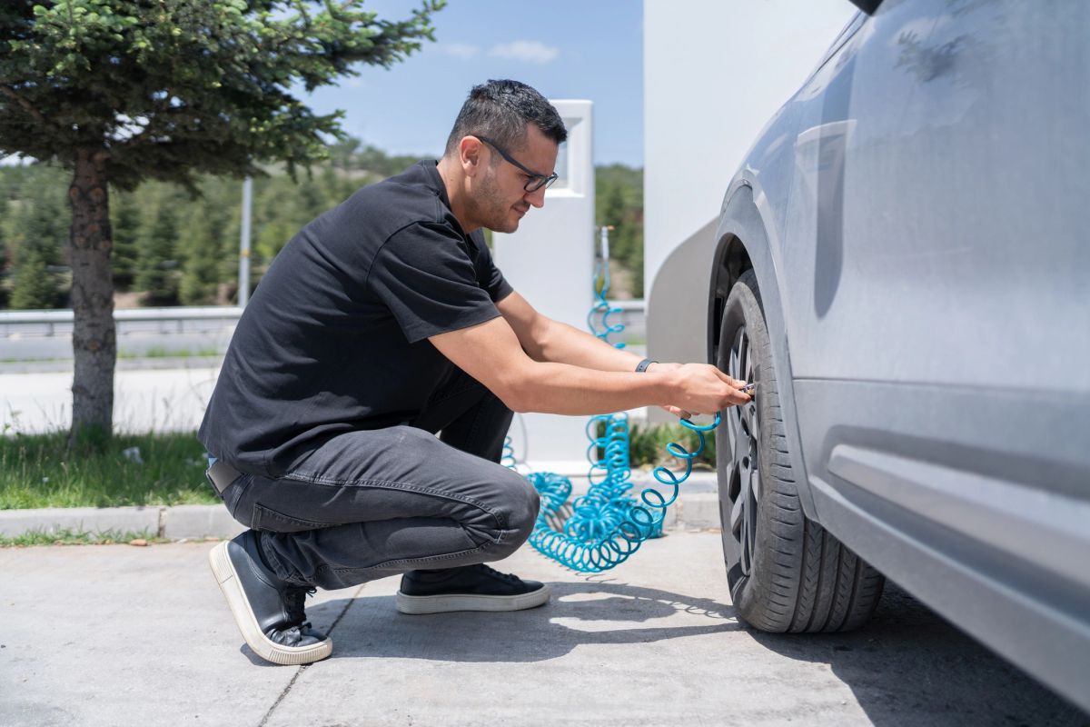 A person checking tire pressure at a service station air pump.