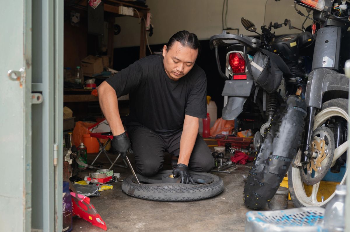 A mechanic in a garage removing a tire from its rim to patch a puncture.