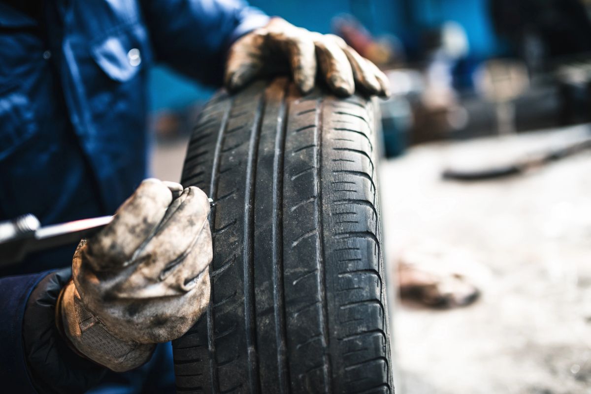 A mechanic's gloved hands inspecting a tire's tread.
